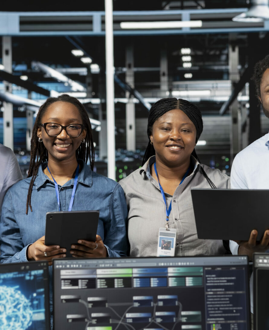 Portrait of happy server farm team looks at data analysis graph to reduce equipment failure. Cheerful data center colleagues look at AI visualization dashboard to pinpoint gear performance glitches